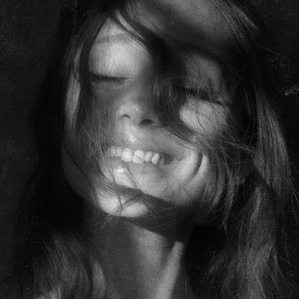 Ariana Grande smiling on the petal album cover